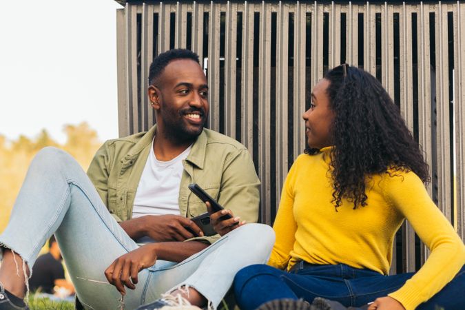 Black couple sitting in a park using mobile