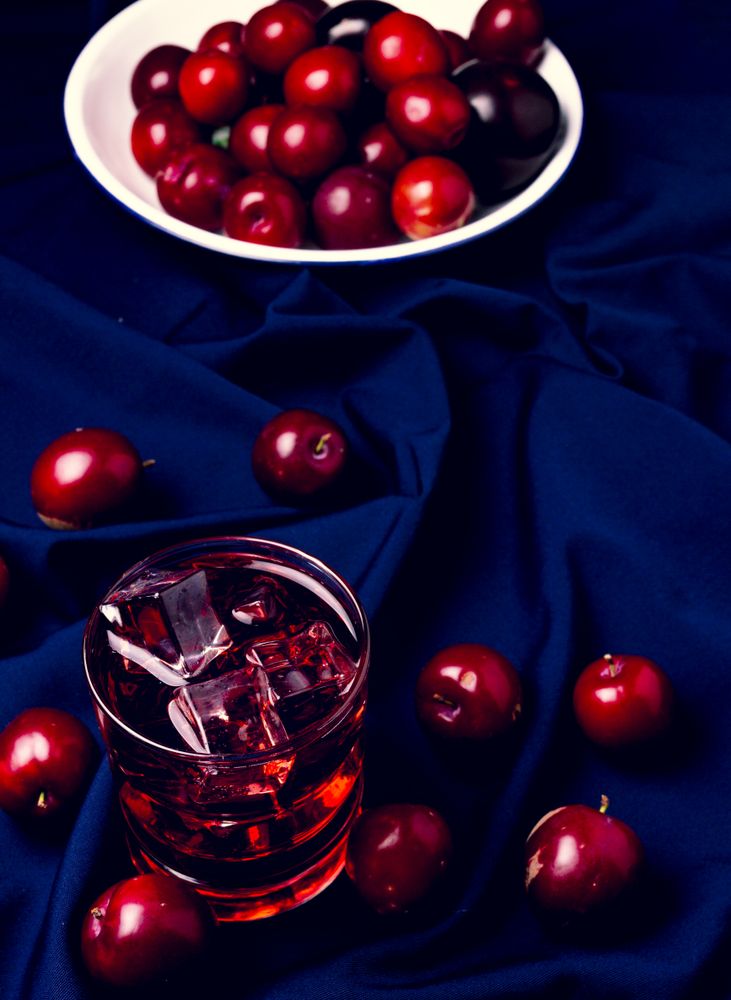 Red beverage near fresh fruits on cloth