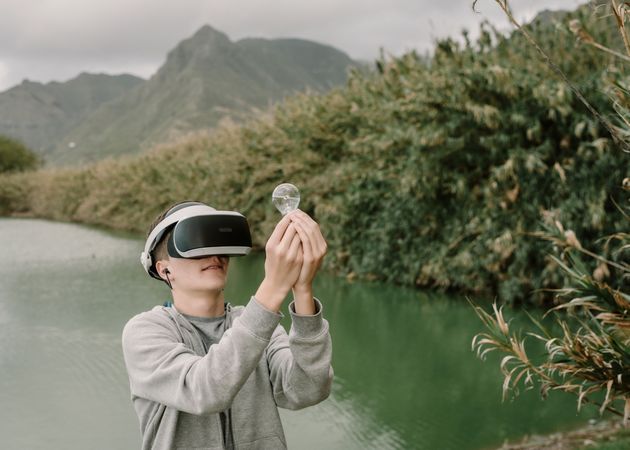 Young teenager with virtual reality glasses holding a light bulb