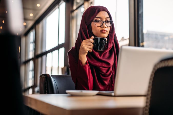 Muslim woman working at a cafe and using laptop computer