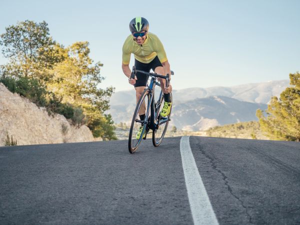 healthy man riding a bicycle on a mountain road in a sunny day