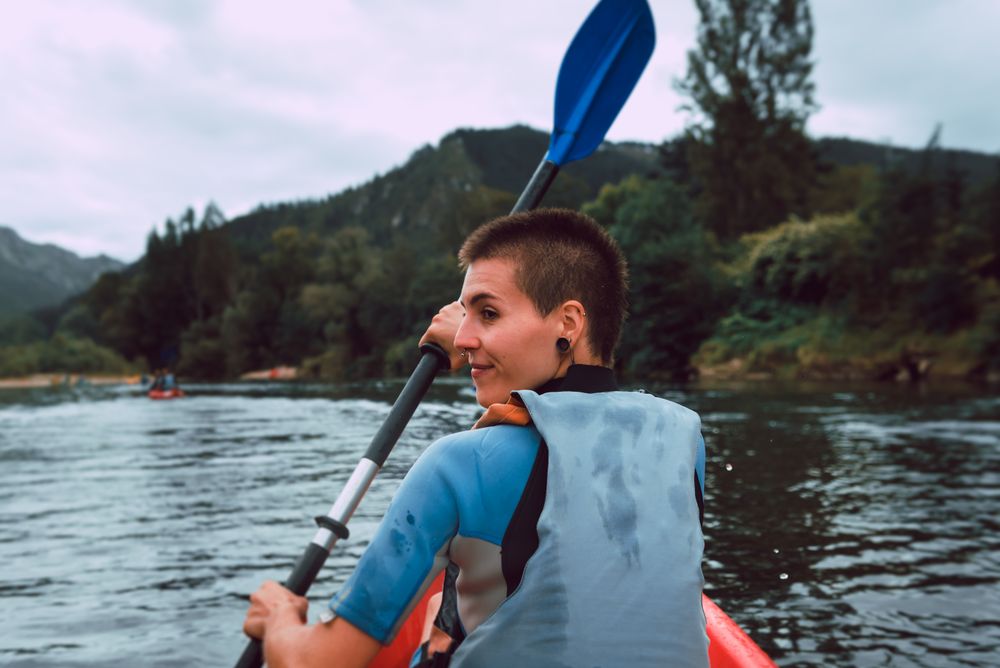 Female kayaking with paddle in raised hands