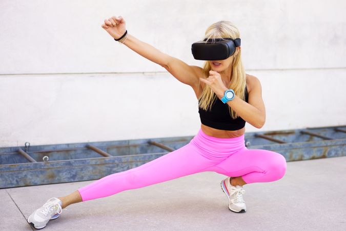 Fit woman doing movement in VR headset