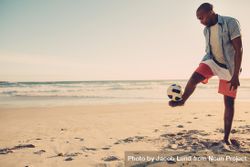 Man balancing a soccer ball on his feet at the sea shore 4d7yE5