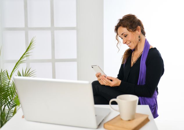 a woman working with a laptop computer answers the telephone