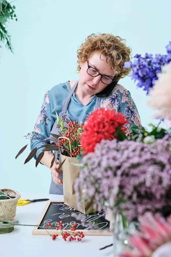 Woman arranging bouquet during phone call in flower store