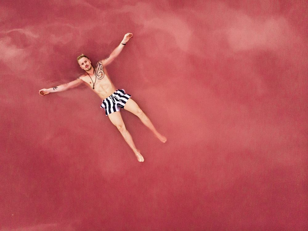 Carefree man on vacation delighting in pink water of lake