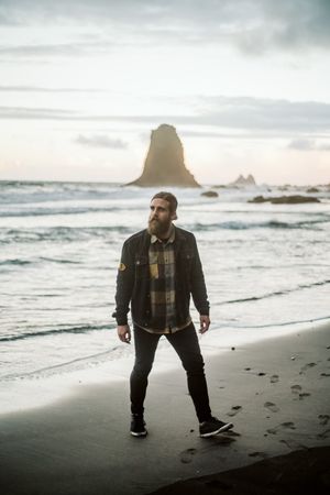 Bearded traveler looking away near sea