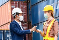 Logistic warehouse foreman giving alcohol gel onsite to worker