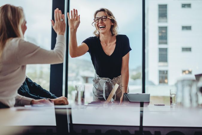 Businesswoman giving high five to colleague in meeting
