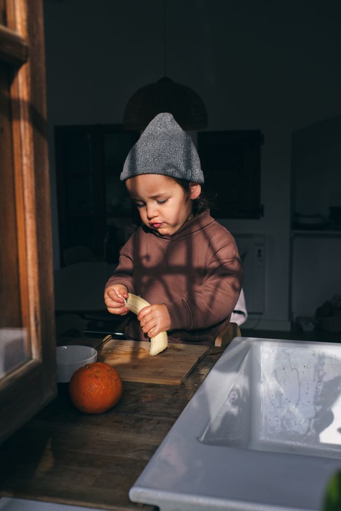 Funny toddler eating banana in kitchen