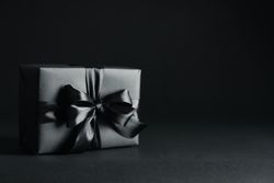Gift box with dark bow on dark background