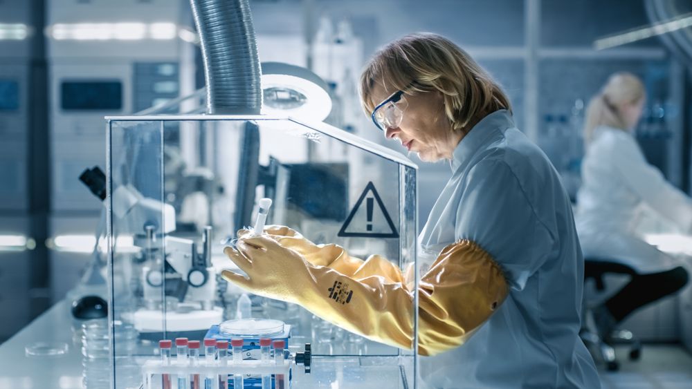 Mature Female Biologist Works with Samples in Isolation Glove Box.