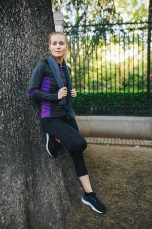 Woman resting on tree trunk after jogging