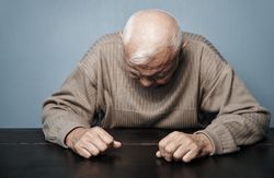 Mature man feeling headache and negative emotions while sitting at the table