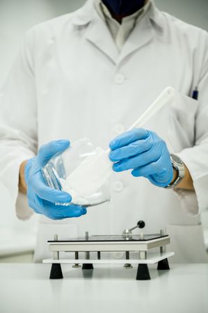 Crop pharmacist pouring powder into capsule filler while preparing medications