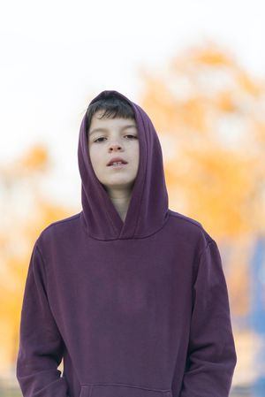 Portrait of a serious teen male in a red hood outdoors