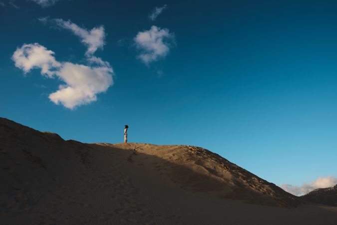 Sun lighted sandy hill with blue sky and white cloud