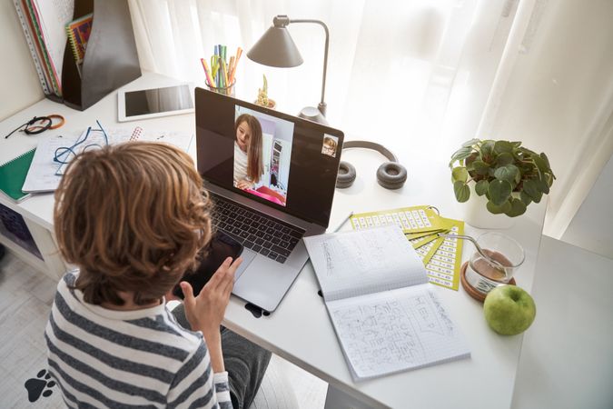 Boy doing homework during video call with classmate