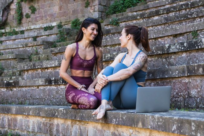 Smiling women sitting on stairs after yoga lesson