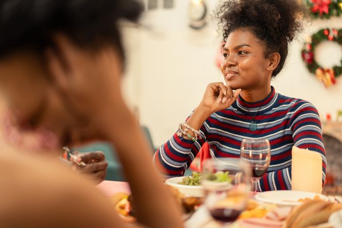 Smiling Black woman enjoying conversation at a festive holiday dinner