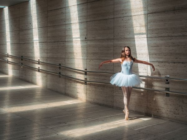 Ballerina doing ballet posing at rail in classroom