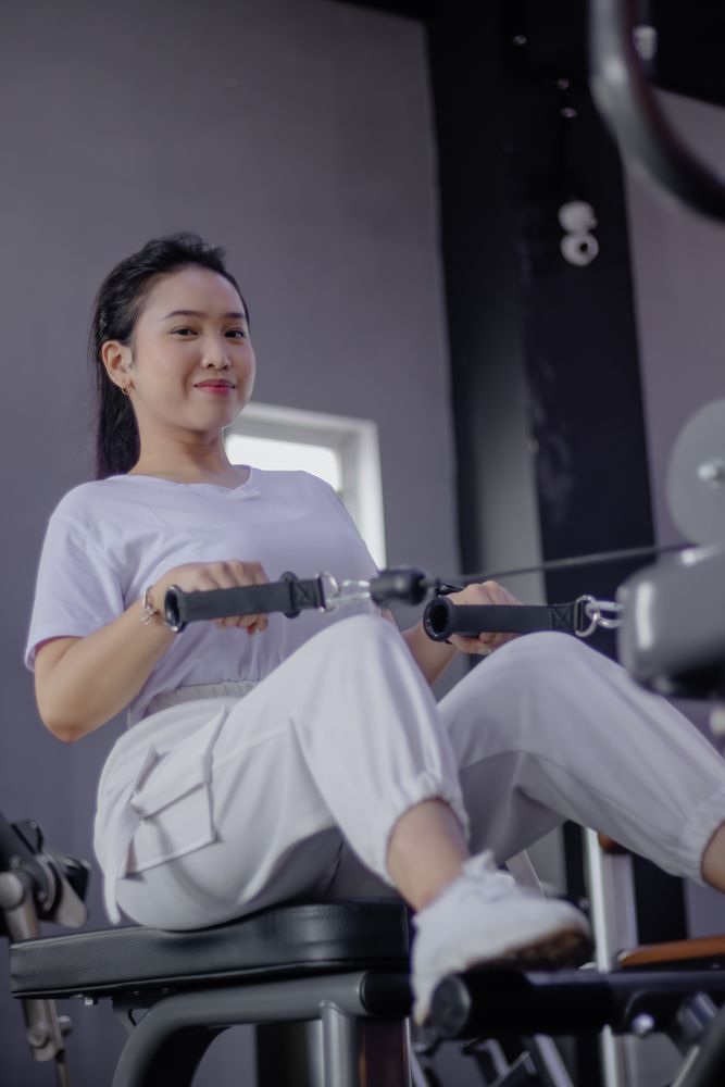 Young woman working out on seated cable row machine at the fitne
