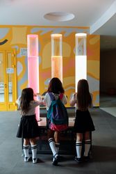 Back view of school girls standing beside an installation on hallway 4NJO84