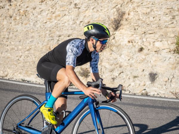 healthy man riding a bicycle on a mountain road in a sunny day