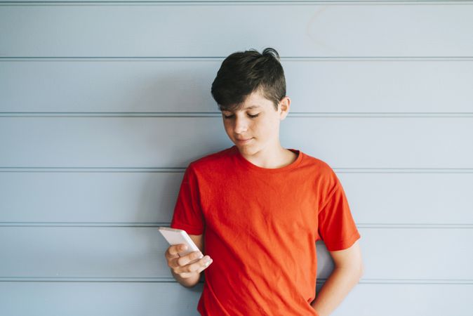 Profile of a calm male teen texting on a smart phone