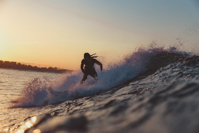 Man on surf board on waving water at sunset