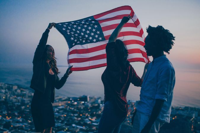 Group of friends uplift the American flag outside