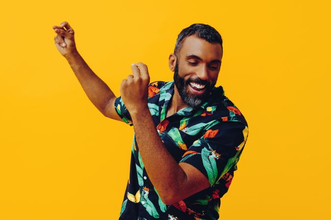 Happy male dancing in brightly patterned shirt, copy space