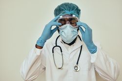 Male doctor adjusting protective eyewear during epidemic