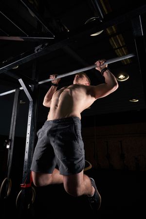 Shirtless sportsman performing exercise on bar