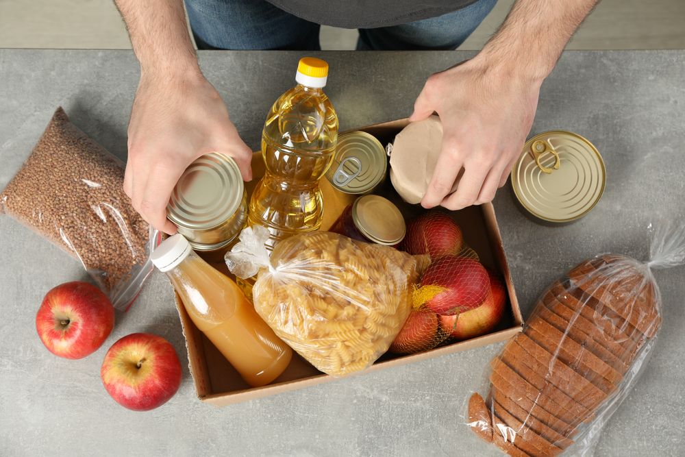 Young man puts groceries in donation box. Volunteer