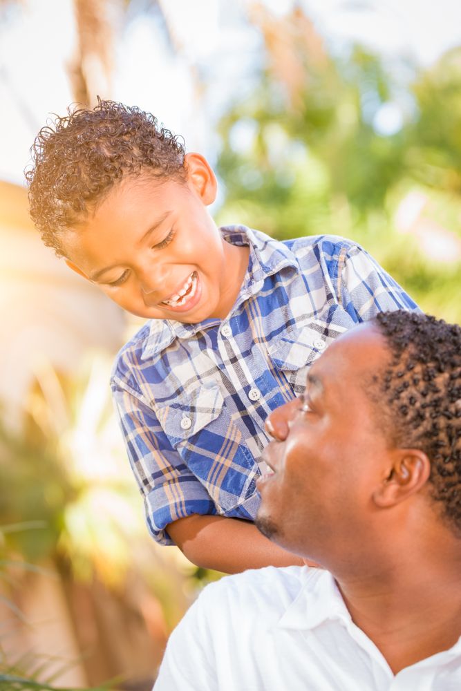 Black Son Smiling With Father Outdoors