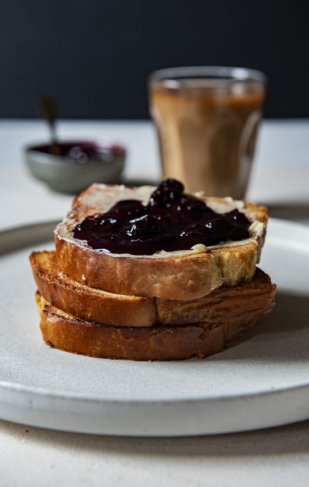 Toasted brioche butter and jam coffee in background