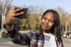 Smiling female taking selfie with park in background