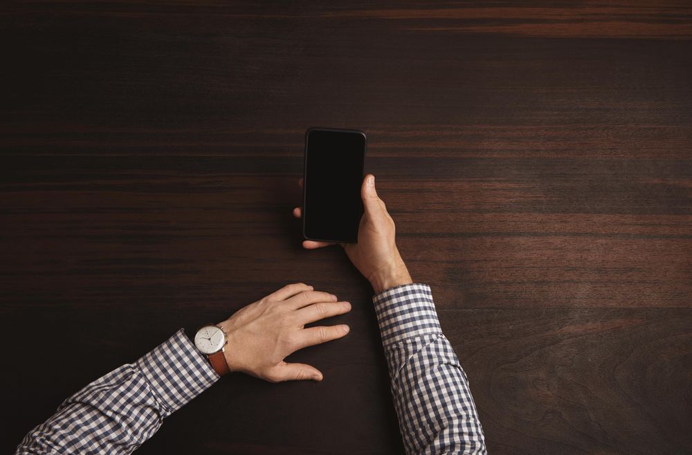 Arms in plaid shirt and watch checking cell phone
