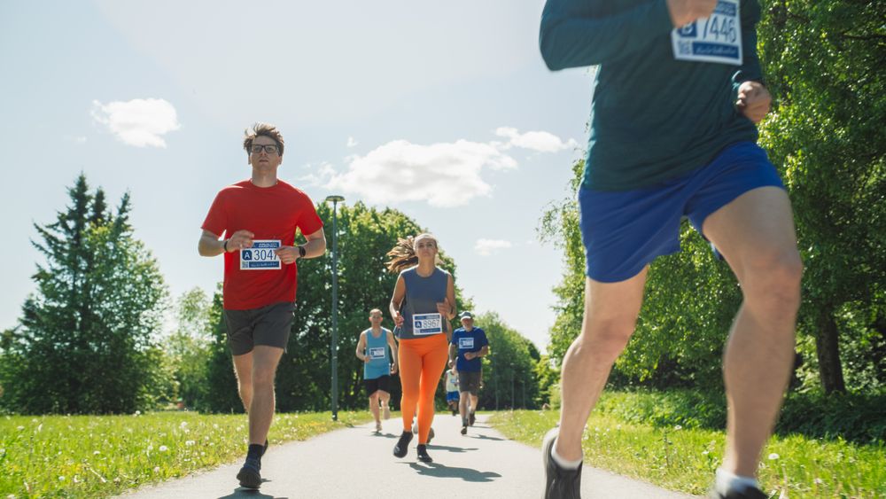 Portrait of a Group of People Participating Together in a Marathon and Running Through a Park Trail.