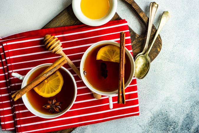 Top view of two tea cups with lemon and star anise on red napkin