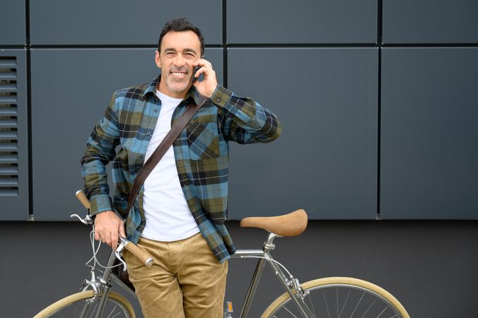 Cheerful man with bicycle talking on phone