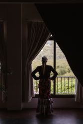 Woman dancer in suit for flamenco standing and looking out window