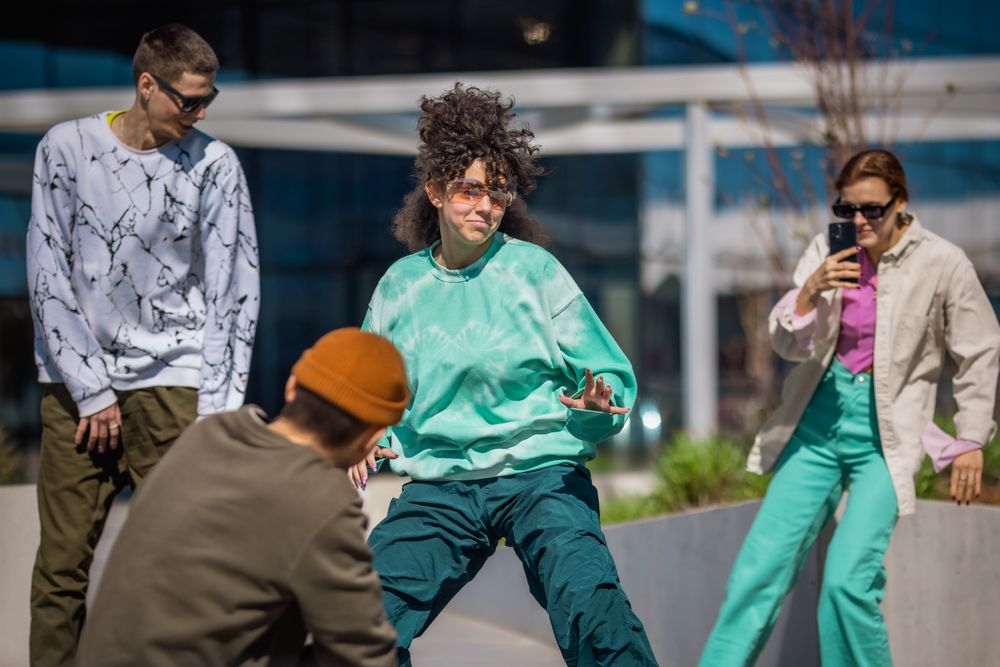 Vibrant Outdoor Scene Capturing A Young Woman With Curly Hair Dancing Energetically