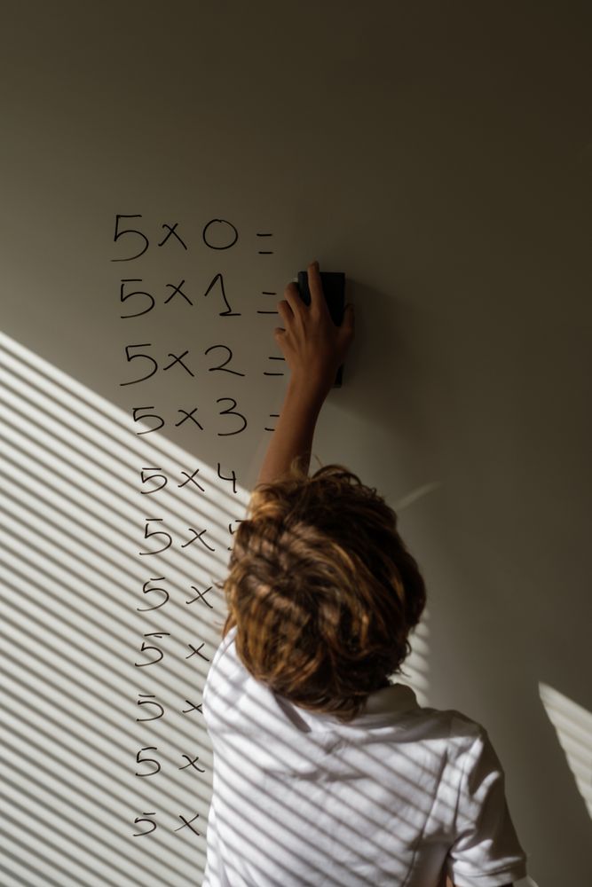 Anonymous schoolkid erasing notes from whiteboard in classroom