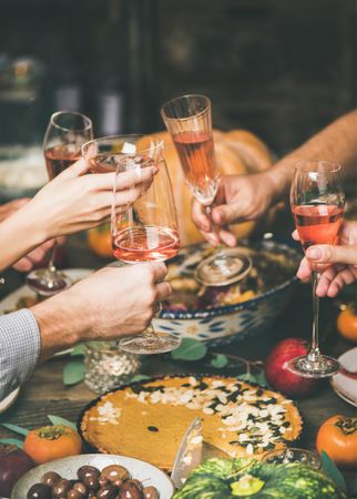 Group of people at festive fall dinner toasting with wine over pie