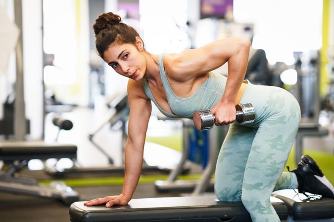 Woman exercising her arms in gym with dumbbell