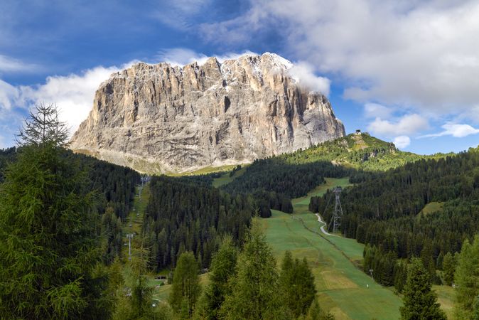 Green trees near gray mountain under blue sky