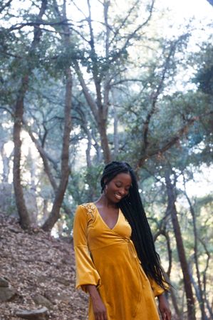 Happy woman with long hair and yellow dress in the woods